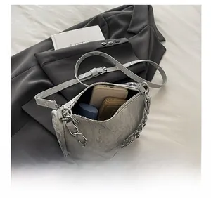 Detailed internal view of grey pleated leather bag with silver chain and daily essentials