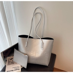 Dettaglio ravvicinato della borsa tote argento metallizzato con scritta TOTE BAG in rilievo