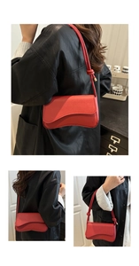 Detailweergave van een rode leren onderarmtas met asymmetrische flap en litchi textuur