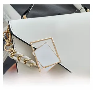 Detail of white textured shoulder bag with gold geometric buckle and chain strap on magazine