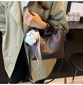 Detail of dark brown woven tote bag with a cute white plush puppy charm accessory