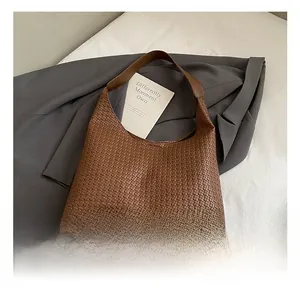 Detailed view of brown woven leather hobo bag on grey suit jacket with inner card detail