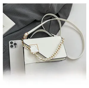White shoulder bag with gold geometric buckle and smartphone for size reference