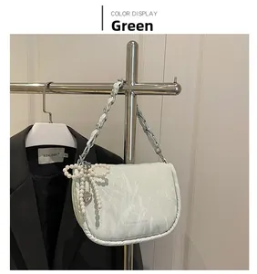 Detail of light green crossbody bag with leather chain strap and pearl heart pendant