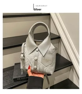 Detail of silver shirt-shaped bucket bag featuring collar and button accents with metallic texture