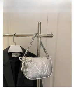 Silver pleated crossbody bag with pearl bow pendant and metallic chain strap