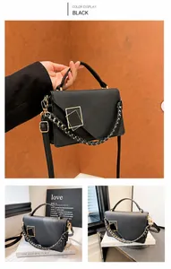 Detail of black matte leather handbag featuring golden geometric buckle and woven chain
