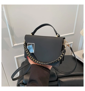 Detail of black matte leather handbag with blue marble buckle and leather chain strap