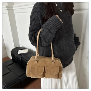 Detail of tan suede tote bag featuring symmetrical flap pockets and silver hardware