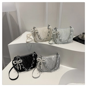 Detail of four colorful pleated fabric handbags with pearl bows and metal chain straps