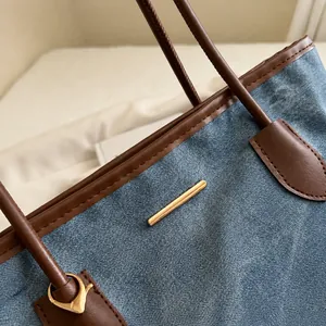 Close-up of blue textured fabric tote with brown leather handles and gold metal accents