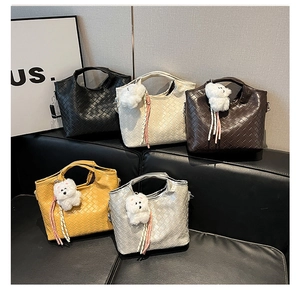 Detailansicht geflochtener Handtaschen in fünf Farben mit süßen Hundeanhängern