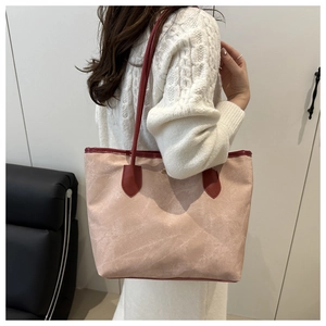 Detail view of large nude pink tote bag with burgundy leather straps and textured fabric