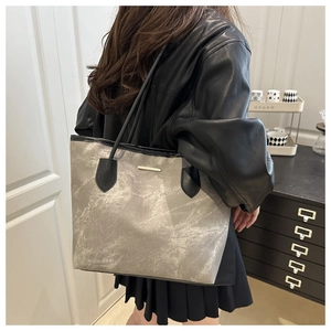 Detailed side view of a grey marble pattern tote bag with gold metal trim for women