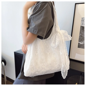 Dettaglio della borsa tote in pizzo bianco con ricamo floreale e un grande fiocco