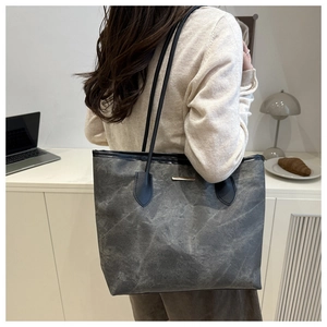Detail of dark gray textured tote bag with black straps in an office setting