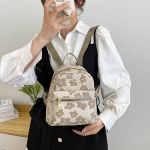 Detailansicht eines beigen Mini-Rucksacks mit Blumenmuster und goldenen Reißverschlüssen