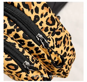 Detail of leopard print crossbody bag featuring smooth black double zippers and nylon texture