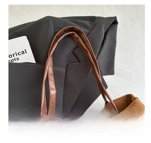 Detail view of brown faux suede tote with leather handle stitching and soft texture