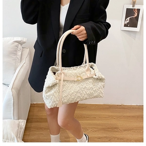 Close-up of cream-colored textured faux shearling tote bag with fine golden buckles