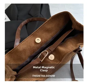 Detail of the golden magnetic buckle closure and brown leather trim on the suede tote bag
