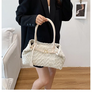 Detail of creamy white sherpa shoulder bag featuring gold buckle and soft fuzzy texture