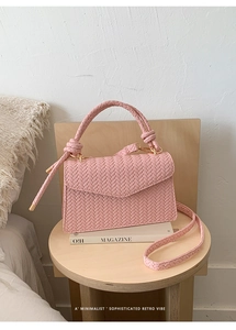 Detail of pink woven texture crossbody bag with gold hardware and braided handle