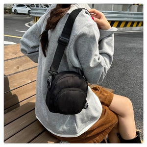 Mini borsa a tracolla regolabile in nylon nero con scomparti a zip indossata da modella