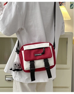 Close-up of red canvas messenger bag with adjustable strap and octopus plush charm