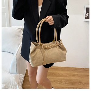 Detail of a beige suede tote bag with long handles and elegant stitching for commuting