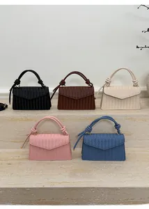 Detail showing five colors of textured weave crossbody bags with knot handles and gold hardware