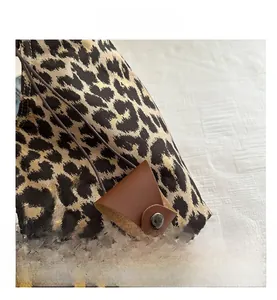 Detalle de bolso de lona con estampado de leopardo, adorno de cuero y botón de presión