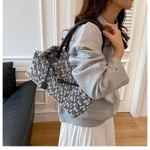 Detailed view of black and white tweed texture and leather handles on tote bag