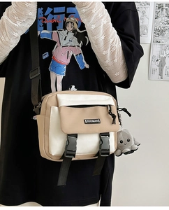 Close-up of a two-tone canvas messenger bag featuring a flap pocket and octopus charm