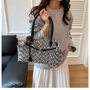 Close-up of black and white tweed tote bag with leather straps and gold buckle