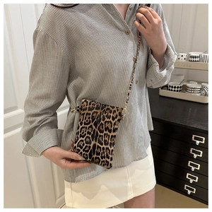 Detail of leopard print faux fur crossbody bag with golden chain strap on a model