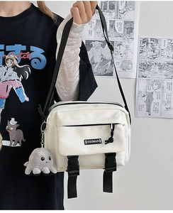 Detail of white canvas messenger bag with black buckles and cute plush octopus charm