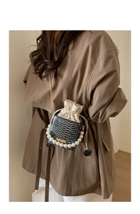 Detail of snake print crossbody bag featuring large pearl handle and metal chain strap