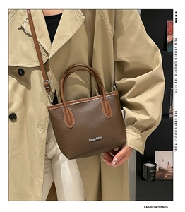 Détail d'un sac à main vintage marron texturé avec logo et poignée supérieure