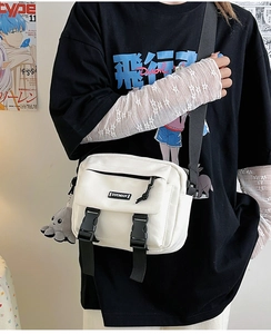 Close-up of a white canvas messenger bag with black buckles and plush octopus charm