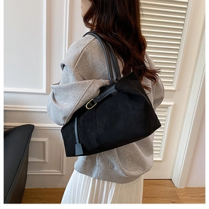 Detail of vintage matte black tote bag with gold buckle side straps and sleek dual handles