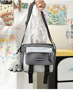 Detail of color-block messenger bag with dual buckles and octopus plush keychain charm
