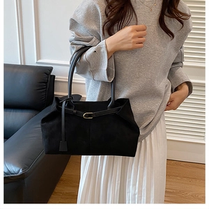 Detail of minimalist black matte tote bag with slim shoulder straps and gold buckle accent