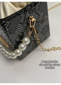 Dettaglio borsa a scatola in pelle di serpente con fibbia dorata e manico di perle