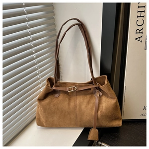 Detail of vintage brown suede tote bag with metal buckle and slim handles in natural light