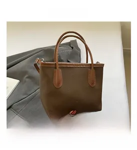 Détail du sac marron foncé avec motif litchi et logo de mode vintage en métal