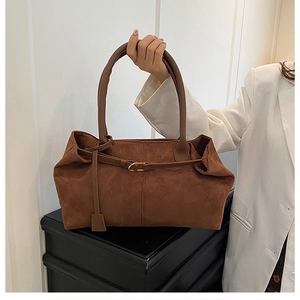 Detail of dark brown matte suede tote bag with gold buckle and slender handles