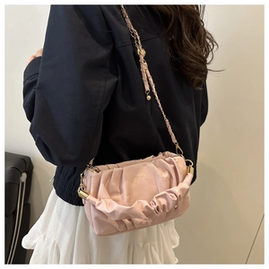 Detail of light pink cloud bag featuring pleated faux leather and gold chain strap