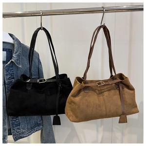 Detail of suede tote bags in black and caramel brown hanging with metallic ring buckles