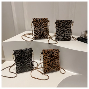 Detailed display of four leopard print mini crossbody bags with chain straps on a white stand
